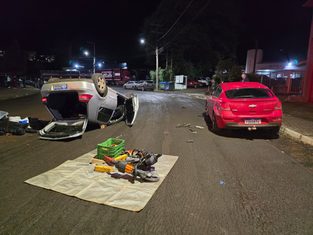 Carro bate em veículo estacionado e capota em avenida de SC